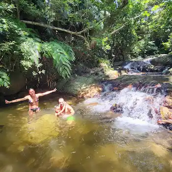 Family swimming and playing at a jungle river waterfall during an Ishigaki shore excursion